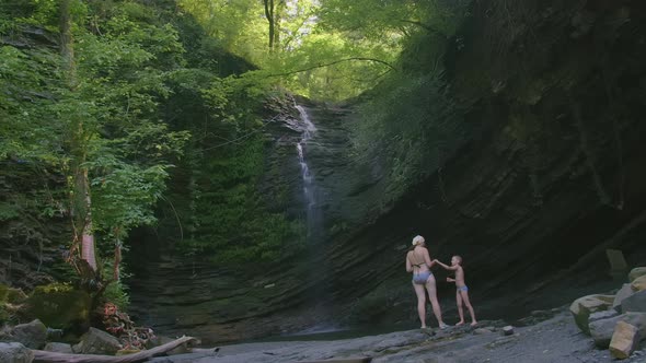 Two People are Standing at the Bottom of a Waterfall