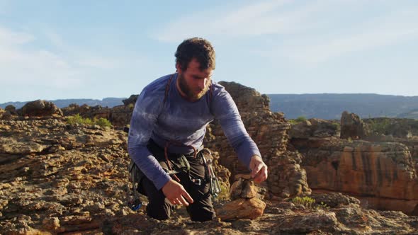 Climber stacks the stone at top of cliff