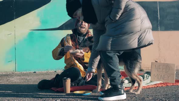 Stranger Gives Money to a Beggar and a Dog Eating in the Street