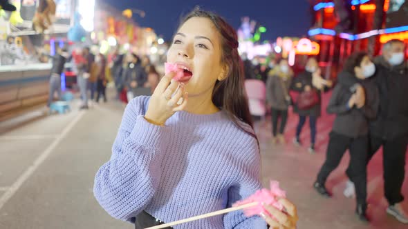 Happy Young Woman Finishing Eating Sugary Candyfloss Standing at a Funfair in Valencia at Night
