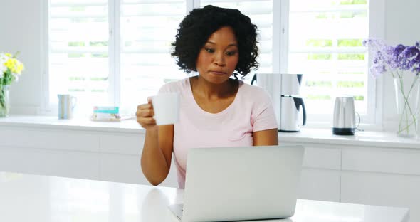 Woman using laptop in kitchen 4k