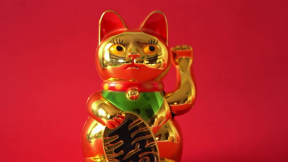 Sitting Maneki-neko cat waving with paw