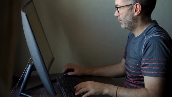 Senior Man is Working in Front of Computer Businessman is Using Large Monitor Sitting at the Table