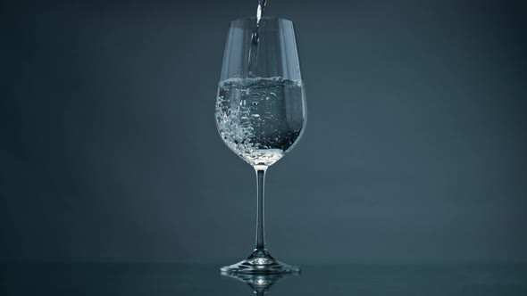 Pure Water Filling Glass at Dark Background Closeup