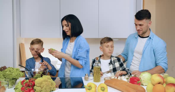 Mother and Father Helping their Sons to Prepare Delicious Vegetable Salad for Family Dinner