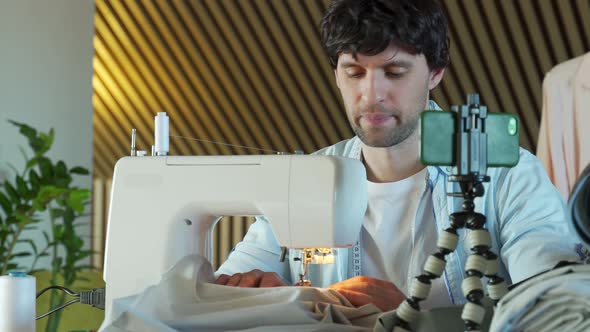 Young Man Shoots a Video Lesson Sews on a Sewing Machine Runs a Blog About Sewing