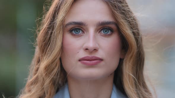 Extreme Closeup Female Serious Face with Natural Makeup Blue Eyes Looking at Camera Posing Outdoors