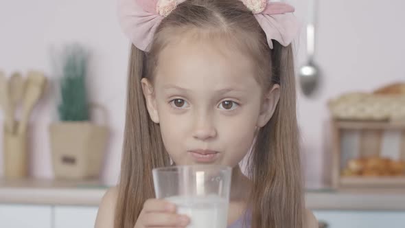 Close-up Face of Cute Little Girl Drinking Milk and Smiling. Portrait of Satisfied Caucasian