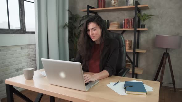 Concentrated Young Woman Freelancer in Black Costume Looking at Laptop Screen, Working Remotely at