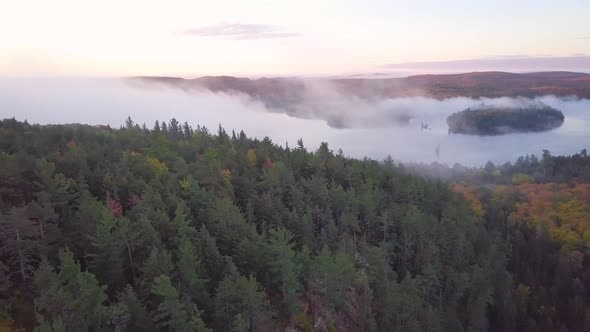Aerial Sunrise Wide Shot Flying Over Fall Forest Colors On Foggy Rocky Ridge Pans Right To Reveal Mi