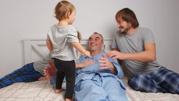 Aged Male Patient Embracing Kids and Talking While Lying on Bed at Home