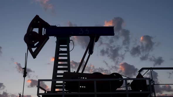 Oil Rig Stands in a Field at Sunset and Extracts Minerals