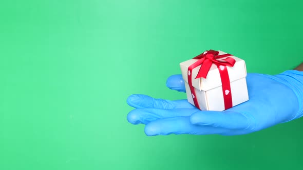 Male Hand in a Blue Medical Glove Gives a Gift.