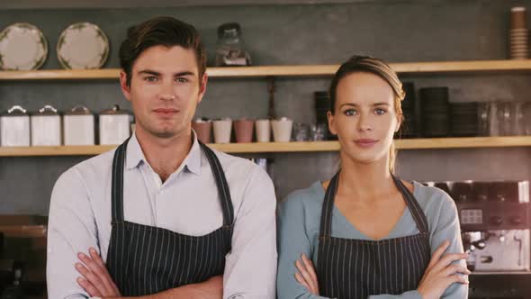 Waiter and waitress standing with their arms crossed