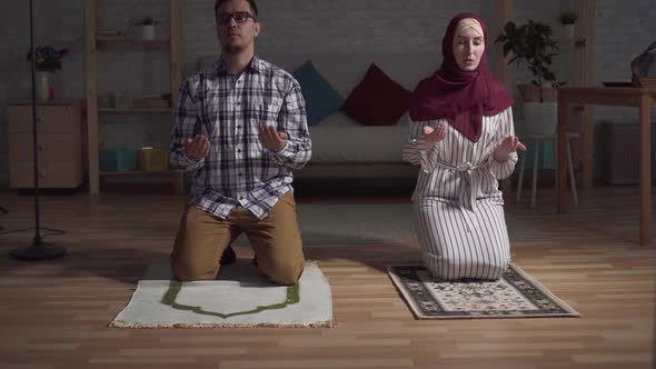 Young Muslim Family Is Praying with Their Hands Up