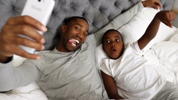 Father and son taking selfie with mobile phone in bedroom 4k