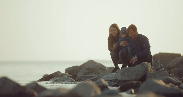 International Family Sitting on the Beach with Stones