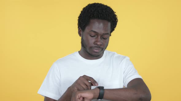 African Man Browsing Internet, Using Smartwatch, Yellow Background