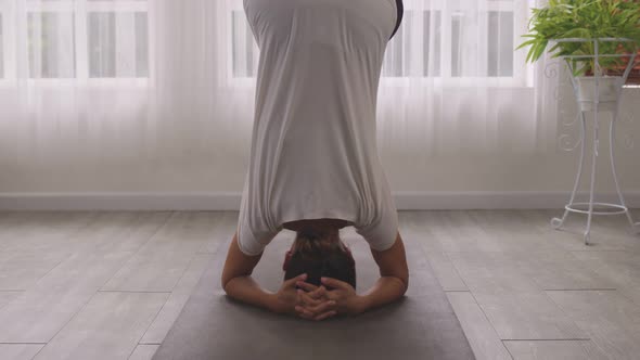 Yoga  Handstand Posture, Vrischikasana on mat, Asian woman in sportswear working out inside.