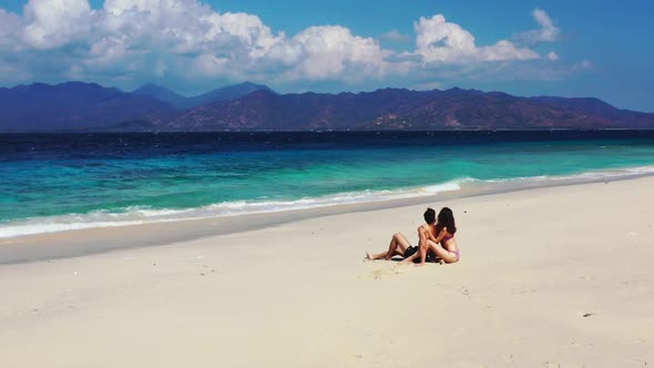 Man and woman sunbathing on exotic tourist beach time by turquoise sea with white sandy background o