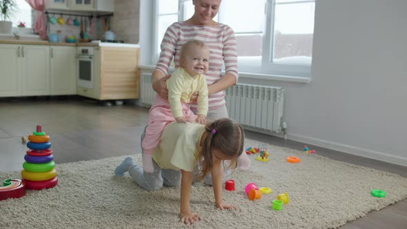 Woman Mother Plays With Two Children Girls Toys In The Room