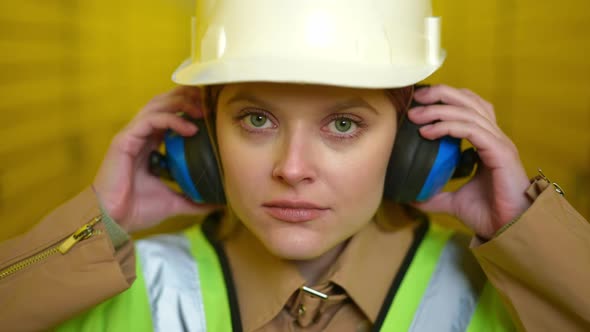 Front View Headshot of Beautiful Caucasian Woman in Hard Hat Taking Off Headphones Looking at Camera