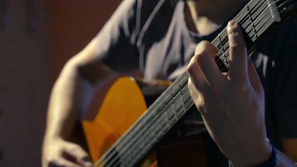 Young man playing classical guitar focusing on advanced fingering techniques with his left hand