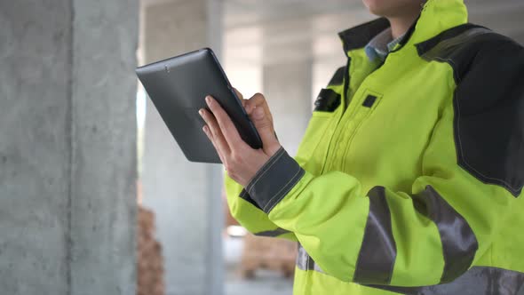 Engineer in Helmets with Tablet Device and Big Paper Drawings Discussing