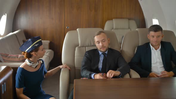 Three Businesspeople Inside of Private Jet Relaxing and Speaking with Stewardess