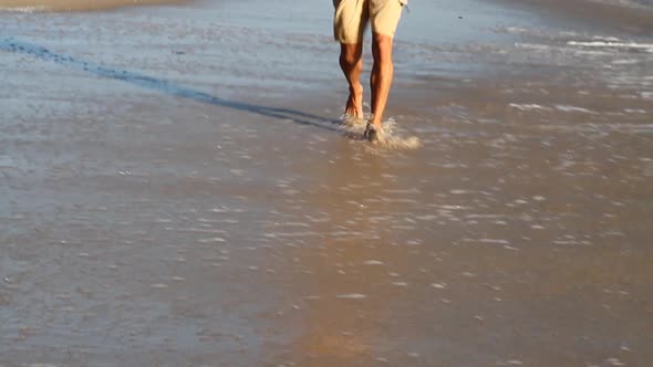 A young man holding his surfboard on the beach.