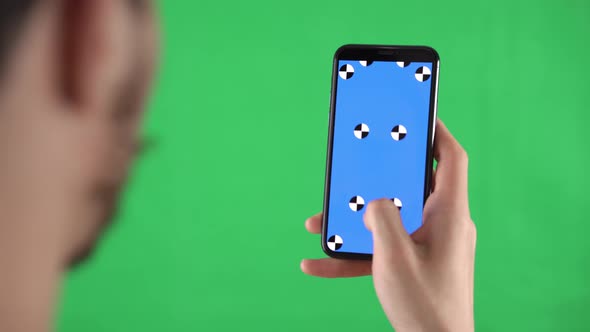 Man is Zooming the Content on the Smartphone with Tracking Markers on Display Against a Green Screen
