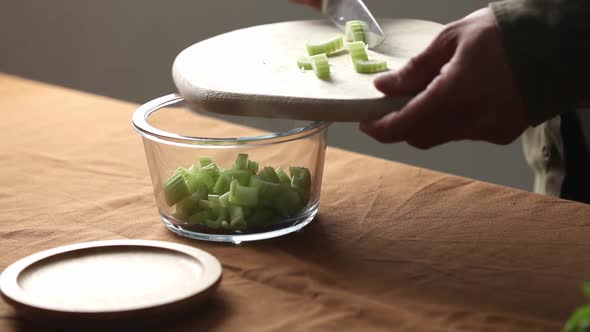 vegetarian man cuts Celery on a chalkboard in the kitchen with a knife