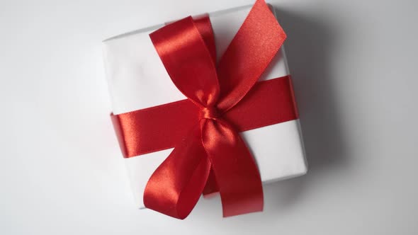 Rotate White Gift Box with Red Ribbon on White Background with Place for your Text