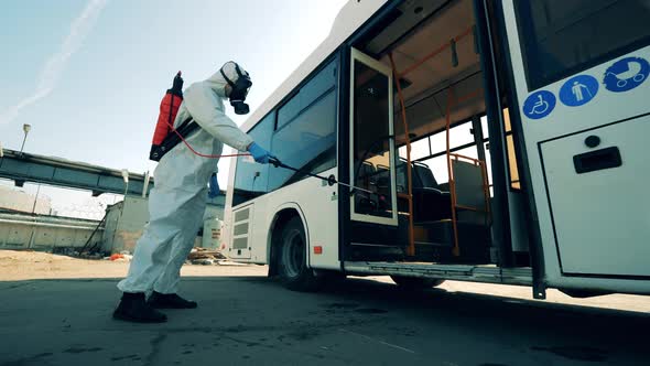 Specialist in a Hazmat Suit Is Disinfecting Bus Entrance. Coronavirus Pandemic Concept, Disinfection