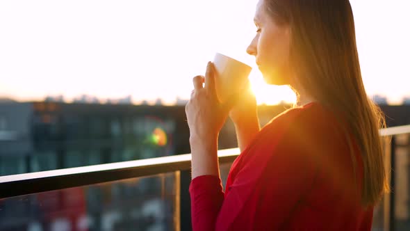 Woman Drinking Coffee While Standing on the Balcony and Admire the Sunset