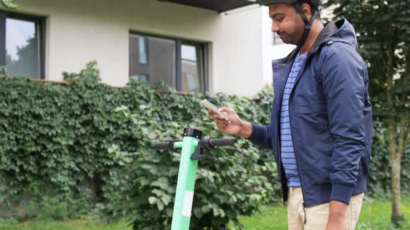 Man with Smartphone Riding Electric Scooter