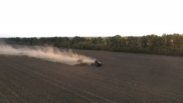 The Tractor Cultivates the Land in the Field and Applies Fertilizer To the Soil - Drone Orbit Shot