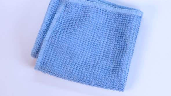 Blue dishcloth rotating over white surface