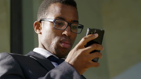 close up on young black african business man texting message with his mobile phone