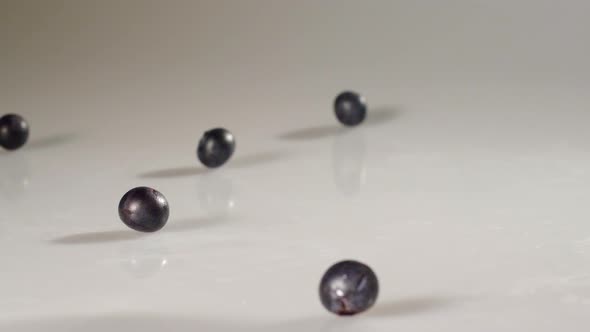 Blueberries poured onto a white surface in slow motion