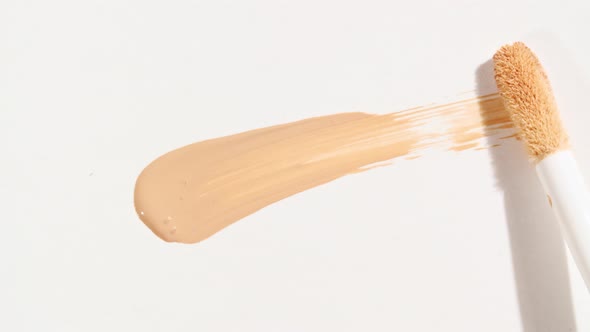 Macro Shot and Slow Motion of a Brush Applicator Smear Concealer Isolated on White Background