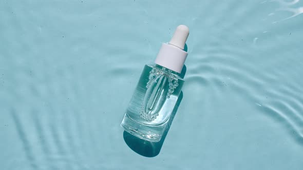 Glass Cosmetic Bottle with Pipette Lies on the Surface of the Water