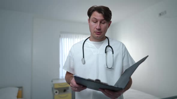 Concentrated Overworking Male Nurse Reading Medical History Sighing Walking Away Leaving Ward