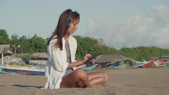 Woman Using Tablet Computer on Beach