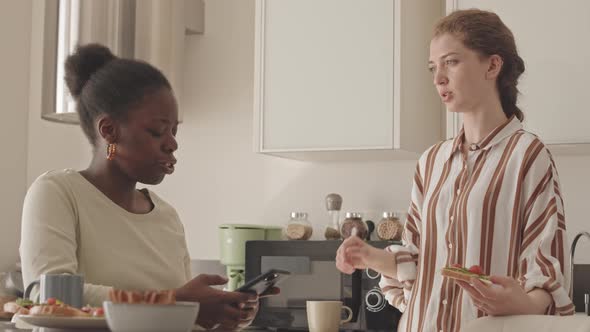 Two Multiethnic Female Friends Talking in Kitchen