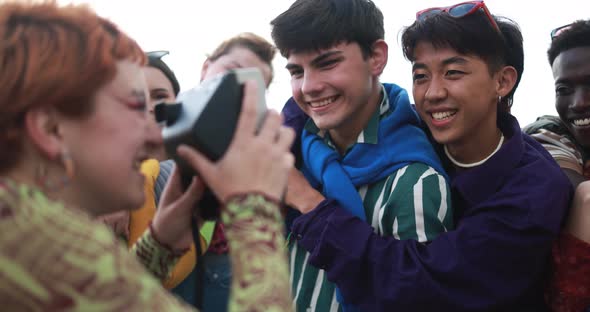 Young diverse people having fun with old vintage camera outdoor