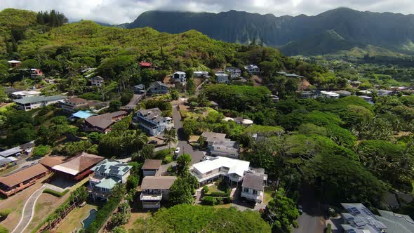 Drone Flying Over Beautiful Kaneohe neighborhood on Oahu in Hawaii, with Mountain Range in the Dista