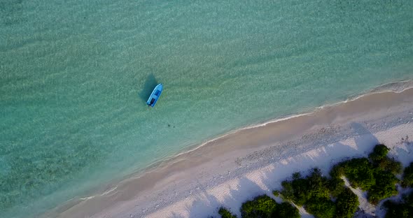 Daytime aerial island view of a sandy white paradise beach and aqua blue water background in vibrant