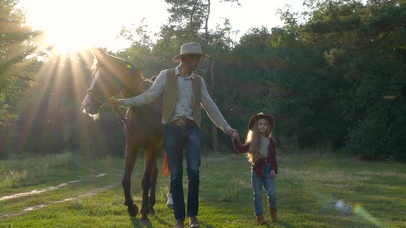 A Cowboy with a Horse and His Beautiful Daughter are Walking in the Pasture