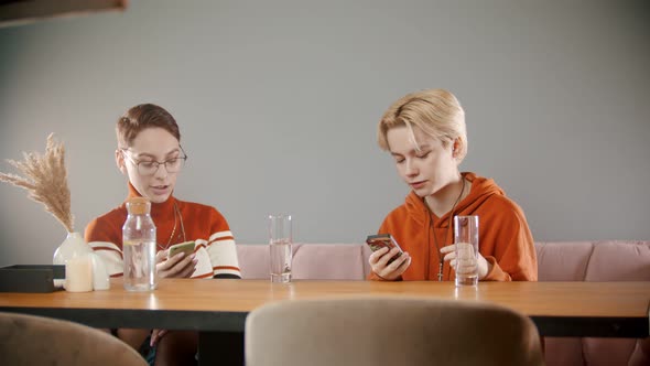 Two Young Girls Are Sitting in Their Phones and Talking To Each Other